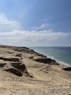 Paragliders soaring above the coastal cliffs of Arica with the ocean below