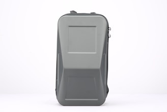 A rectangular, hard-shell case with a smooth gray surface. The case has a robust and sturdy design with a zipper running down its side and a handle on top for easy carrying.