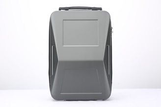 A modern, sleek suitcase with a hard shell design and a matte gray finish. The suitcase features clean lines and a rectangular shape, with a handle on top and subtle patterns that add a touch of style.