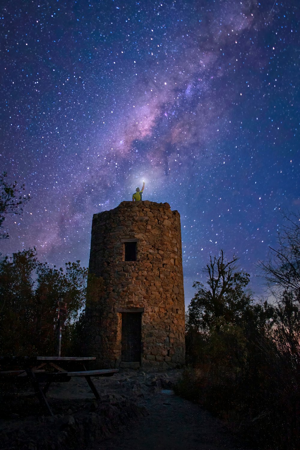 a stone building with a statue on top and stars in the sky