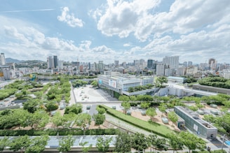 A vibrant cityscape showing a mix of modern buildings and green public spaces.