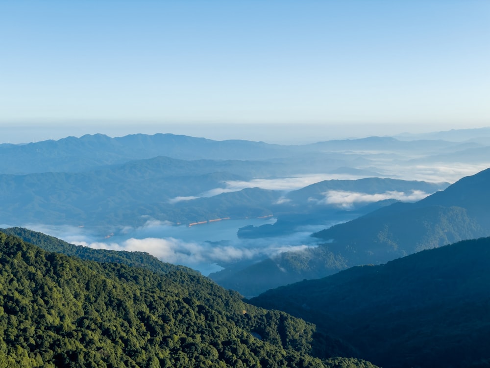 a view of a valley with clouds and mountains in the background