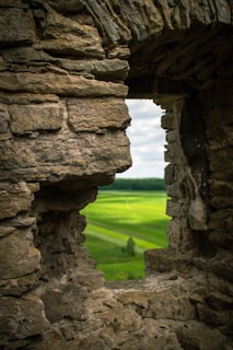 a stone archway with a field in the background