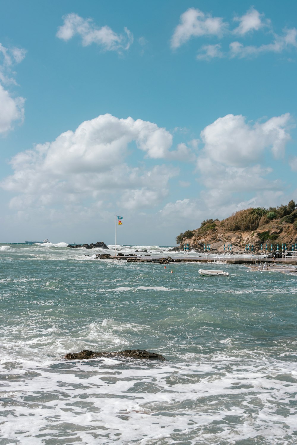 a body of water with a beach and a flag on it