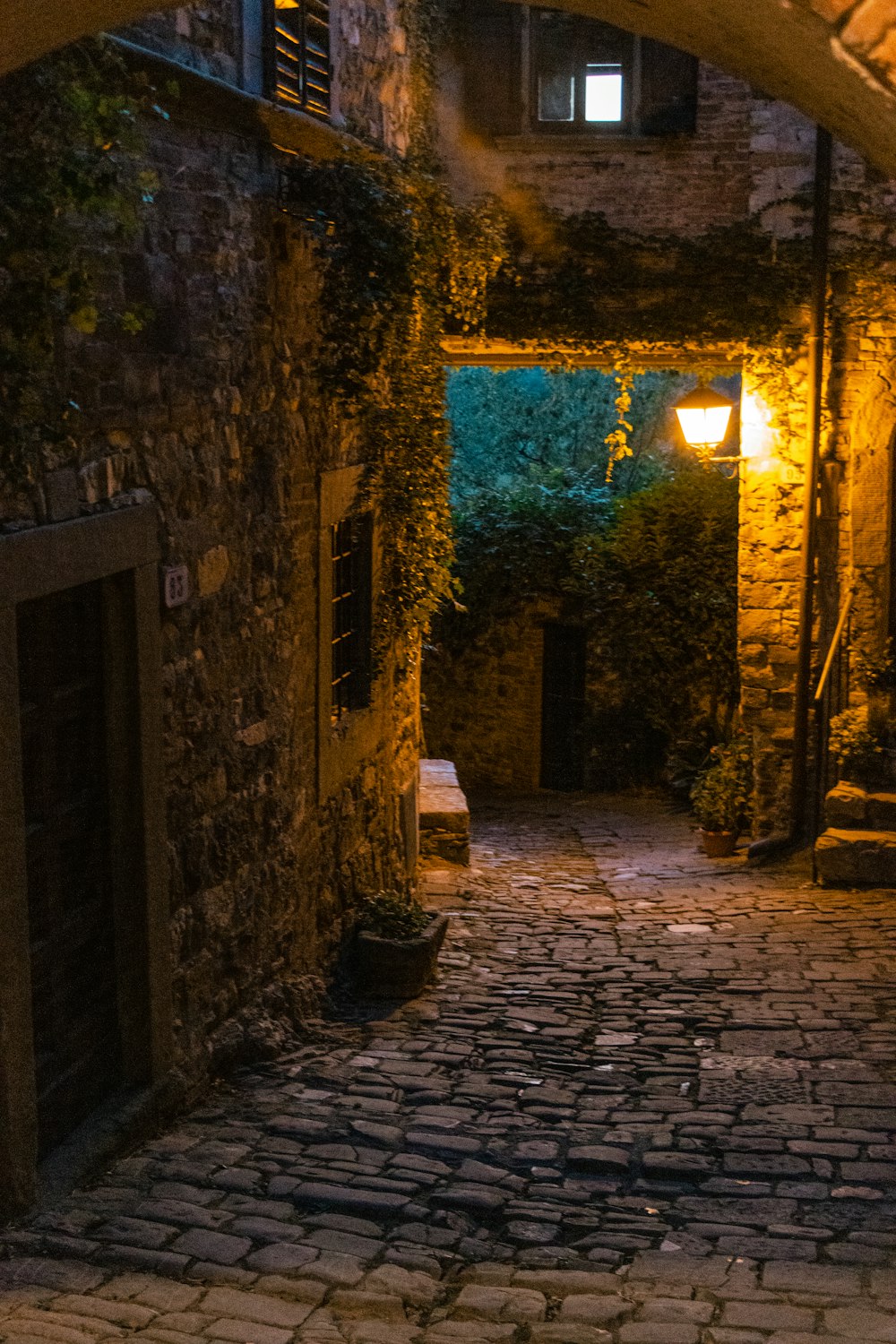 una strada di pietra con un edificio in pietra e una luce sul lato