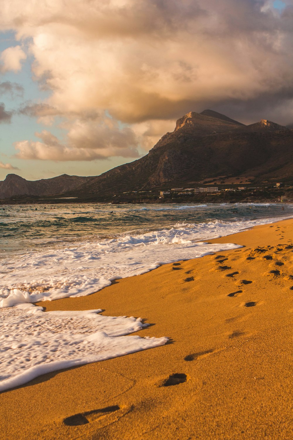 a beach with a body of water and mountains in the background