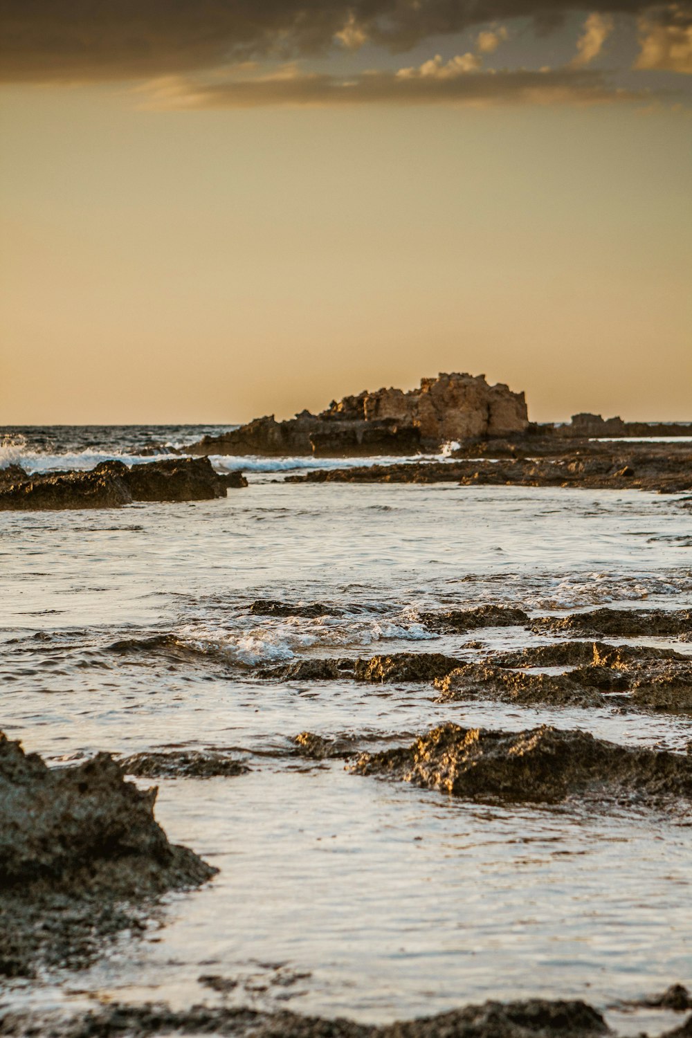 a rocky beach with a large rock in the distance