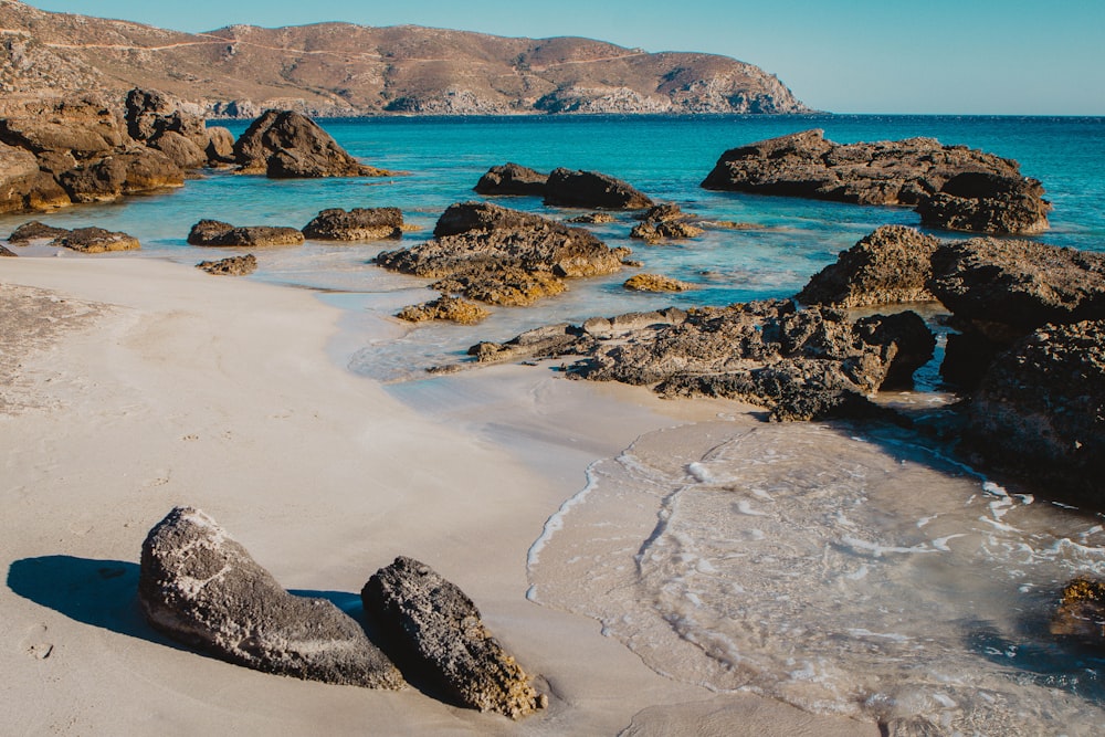 a rocky beach with a body of water in the background