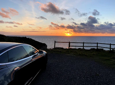 A sleek sedan parked by the beachside in Visakhapatnam at sunset.