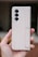 A hand is holding a beige Samsung smartphone with a foldable design. The phone has three rear cameras aligned vertically and a sleek, minimalistic appearance.