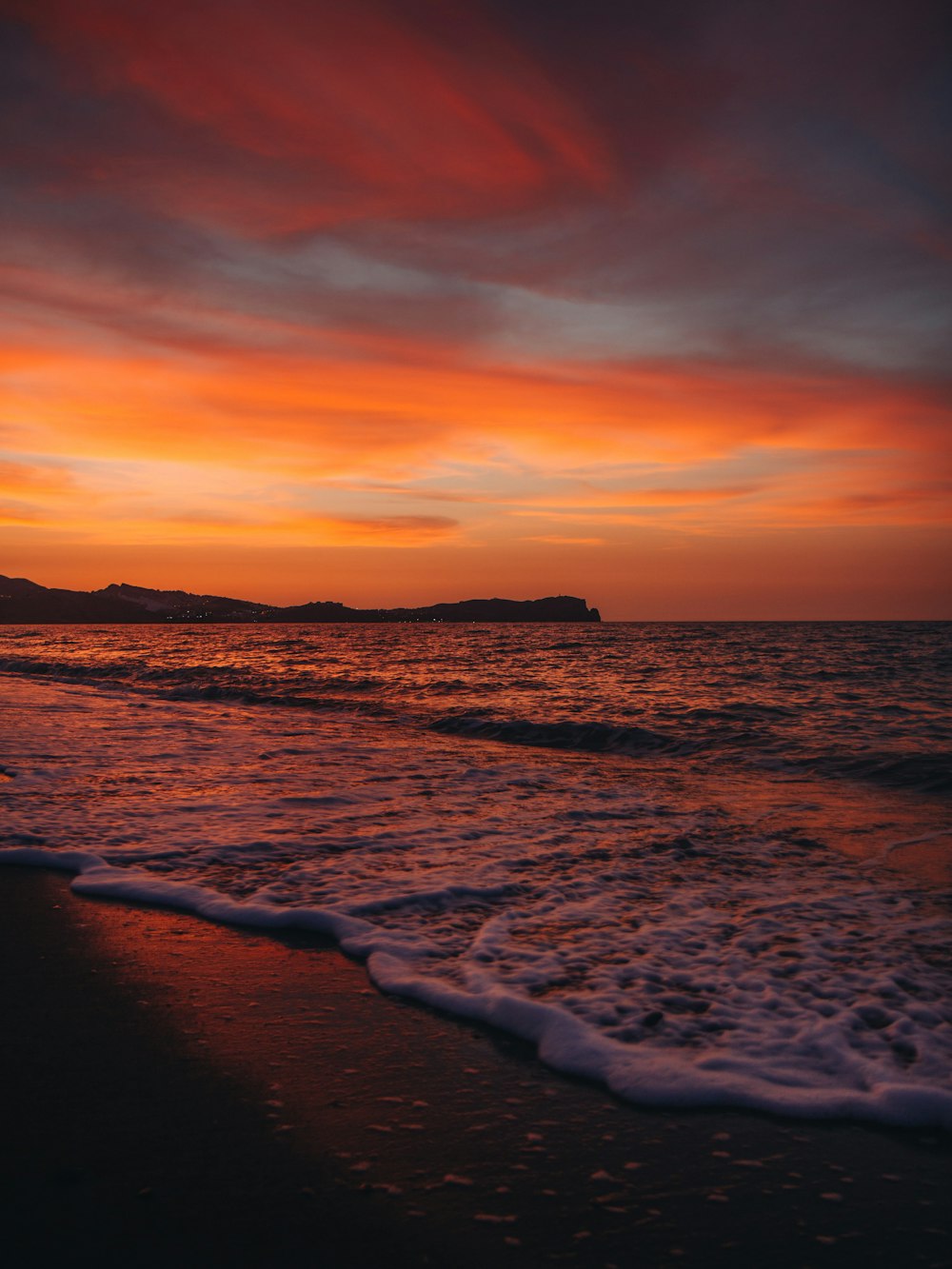 Una playa con olas y una puesta de sol