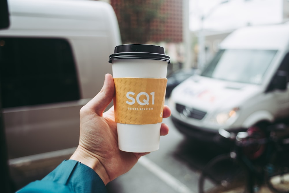 a hand holding a coffee cup