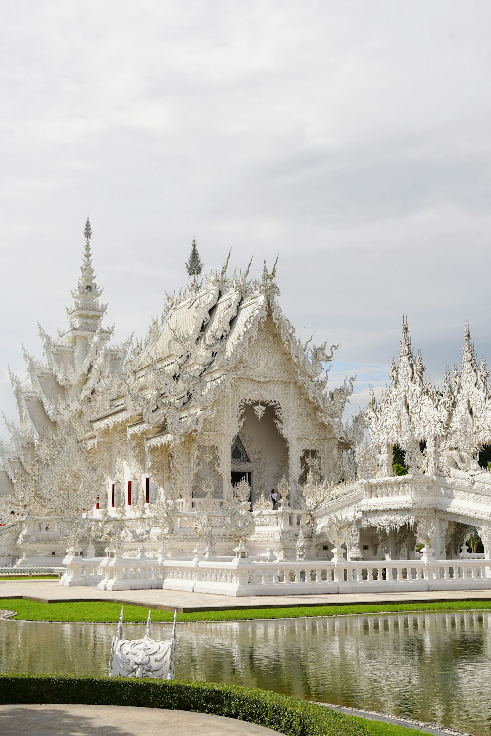 a white building with towers and spires with a pond in front