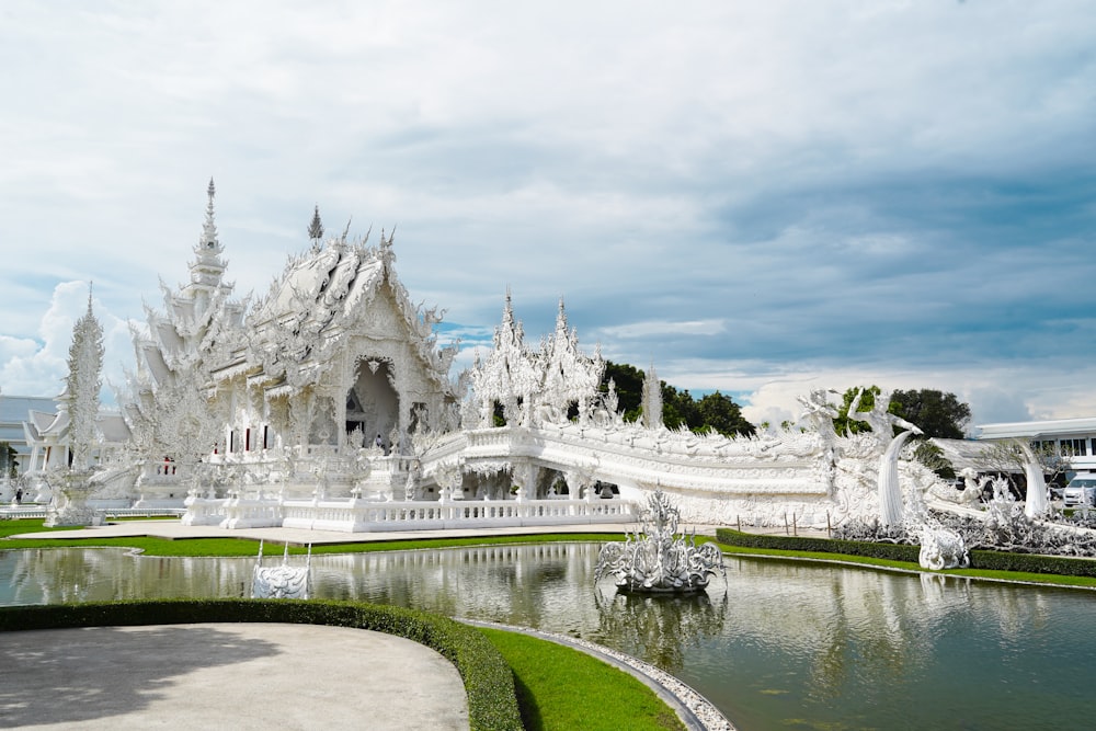 un grand bâtiment blanc avec des tours et de l’eau devant lui