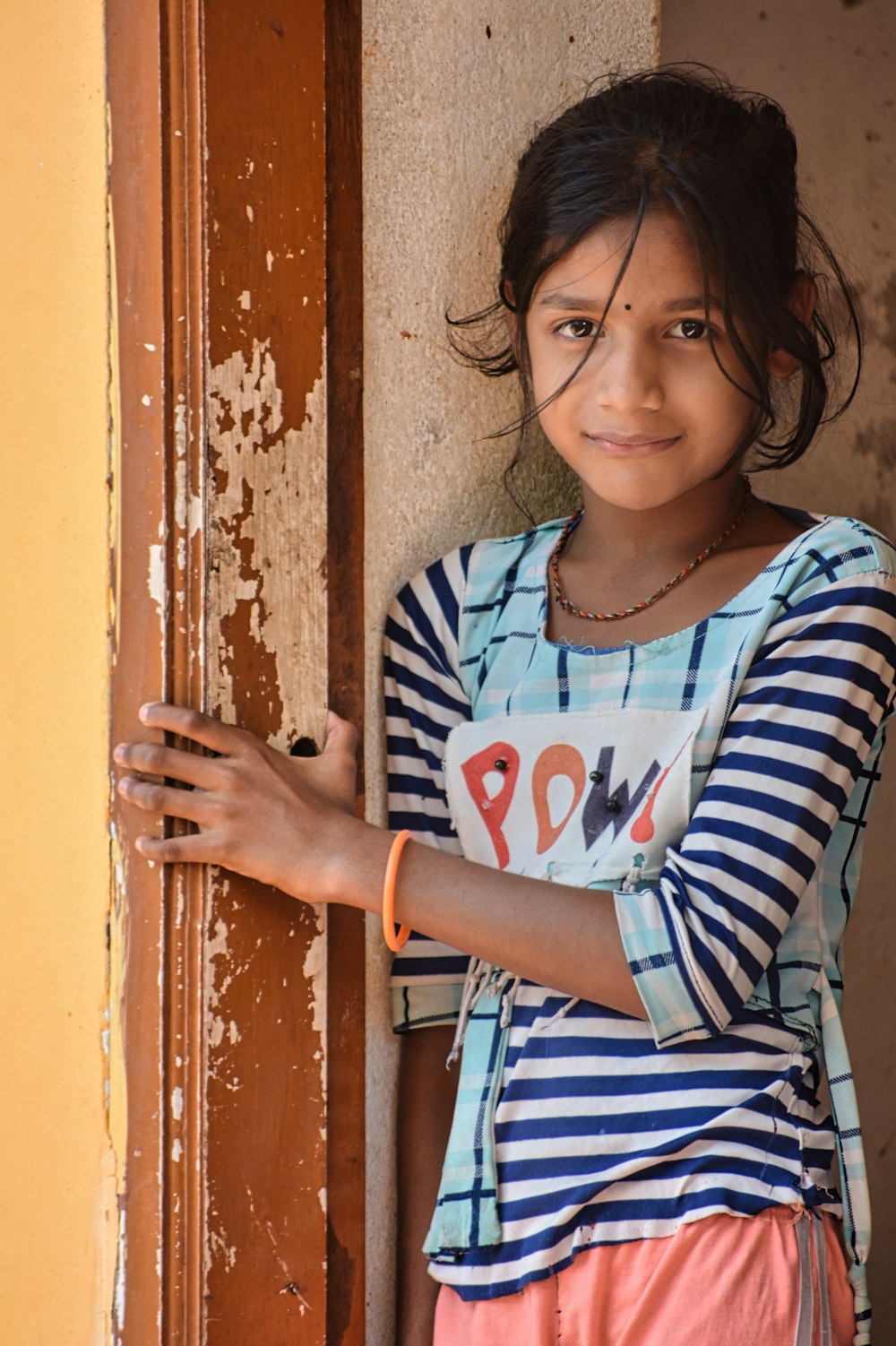 a young girl leaning against a door