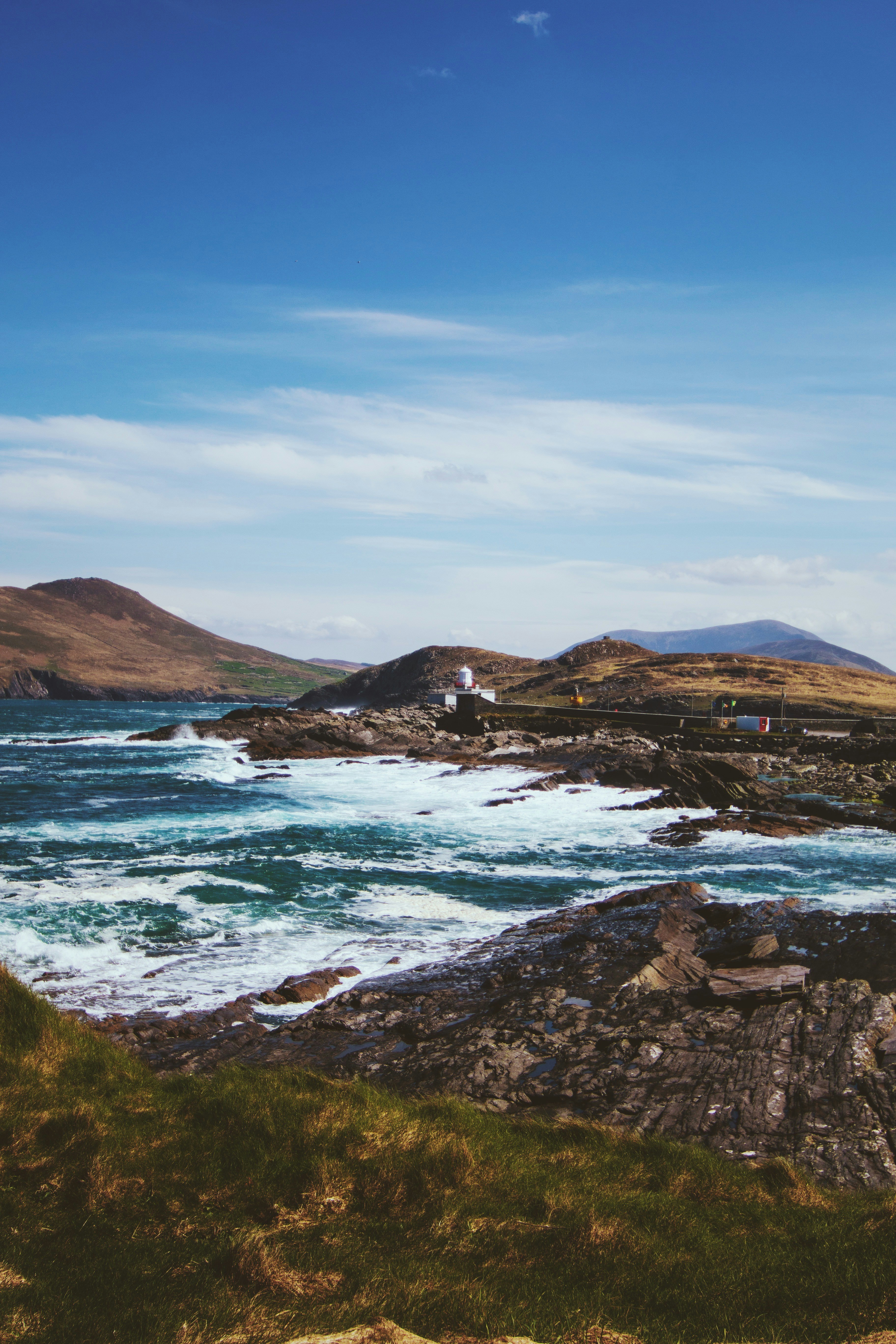 a body of water with rocks and a building on the shore