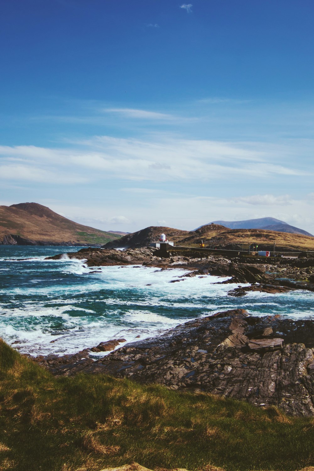 a body of water with rocks and a building on the shore