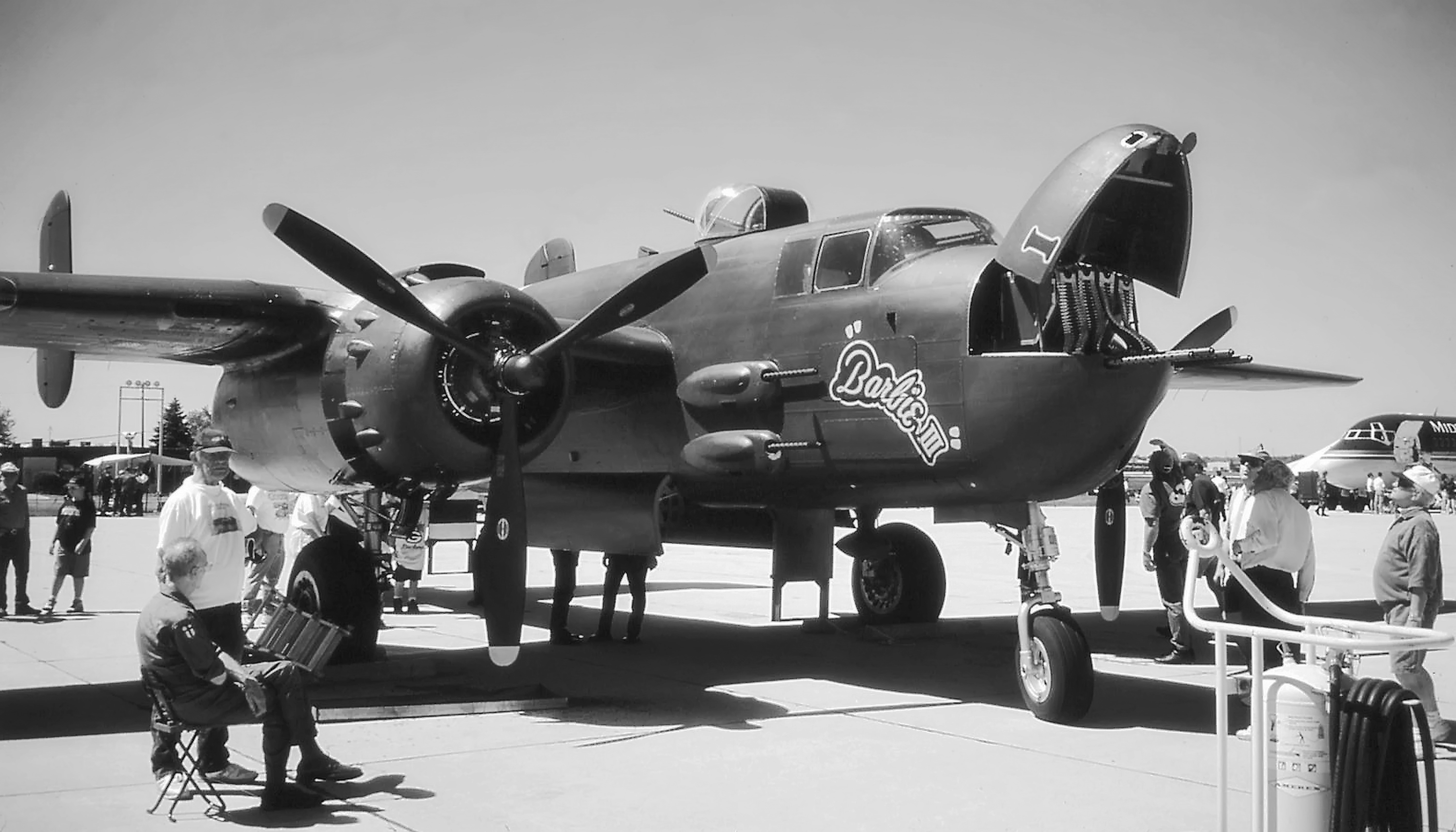 a group of people standing next to an old airplane, American B-25 WW2 bomber. Photo was made from scanned 35mm film.