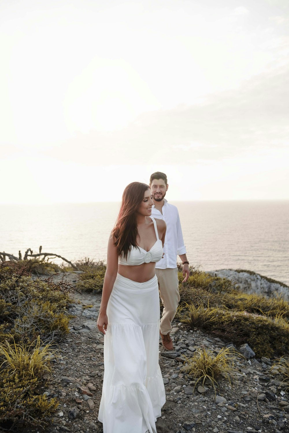 a man and woman posing for a picture on a rocky beach