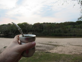 Lifestyle image of a person enjoying a drink with a metal straw outdoors.