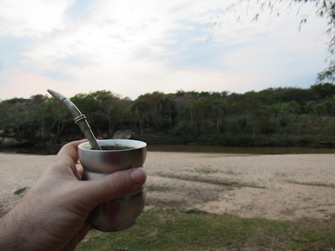 Lifestyle image of a person enjoying a drink with a metal straw outdoors.