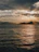Golden sunset casting warm light over the sea with Mount Kinabalu silhouette.