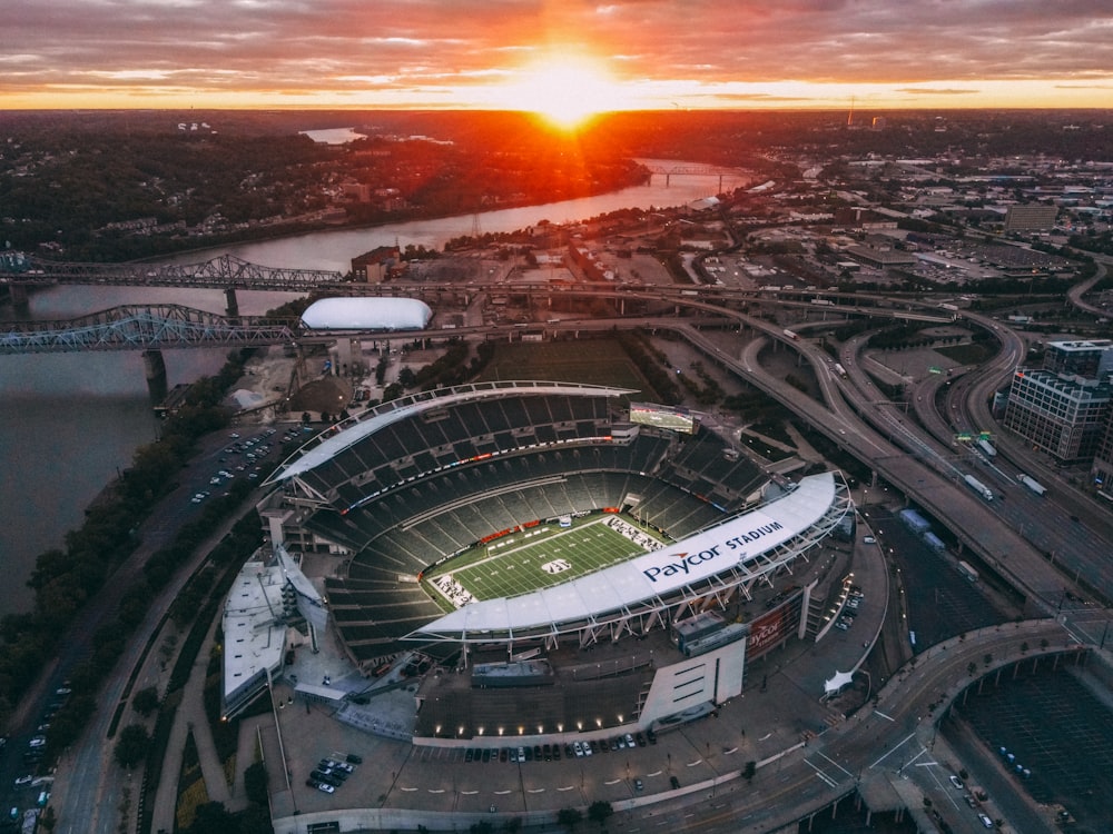 a stadium with a field and a sunset in the background