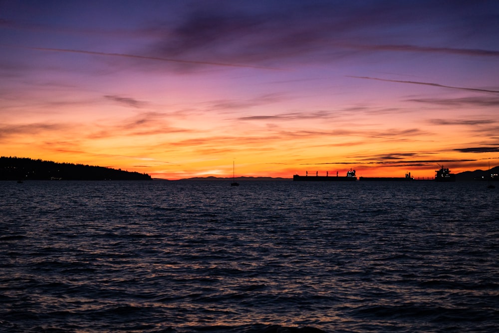 a body of water with boats in it and a sunset in the background