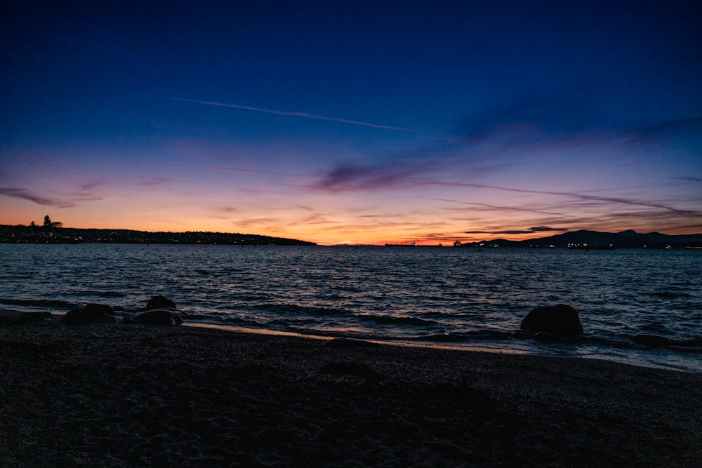 a beach with a body of water and a sunset