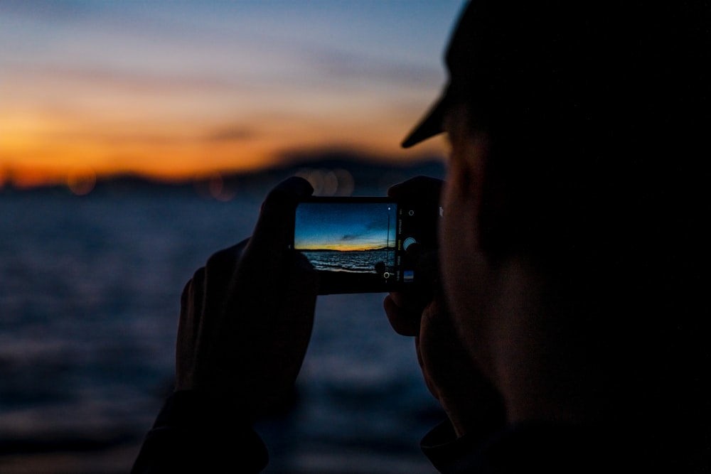 a person taking a picture of the sunset