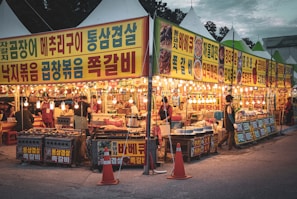 A bustling street market in Seoul with lanterns and local food stalls at dusk.