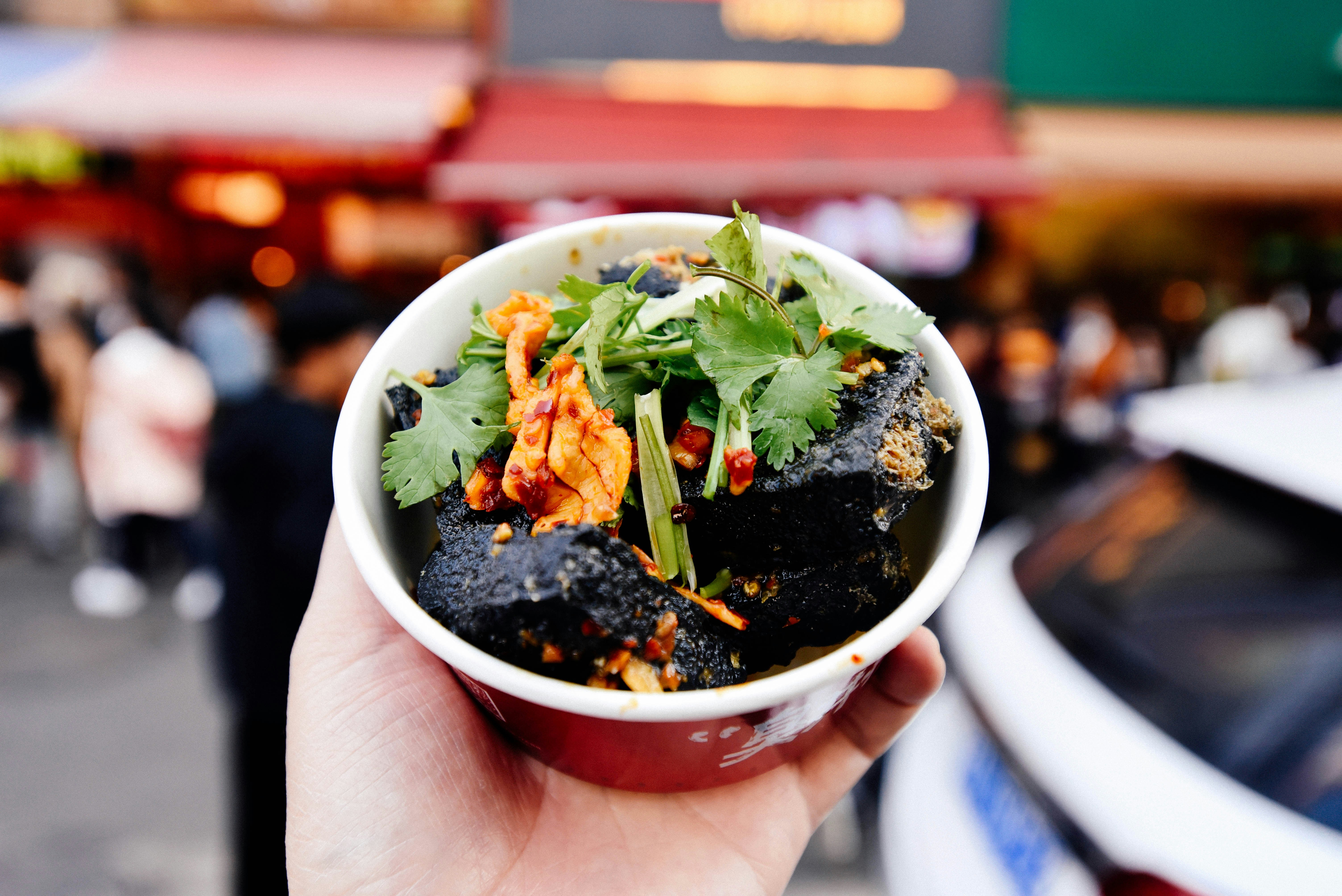 Hand holding a bowl of street food