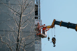 Aerial view of the 26-meter basket crane lifting workers for facade maintenance on a modern building.