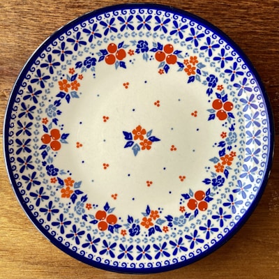 A rustic ceramic plate with a hand-painted floral design resting on a wooden table.