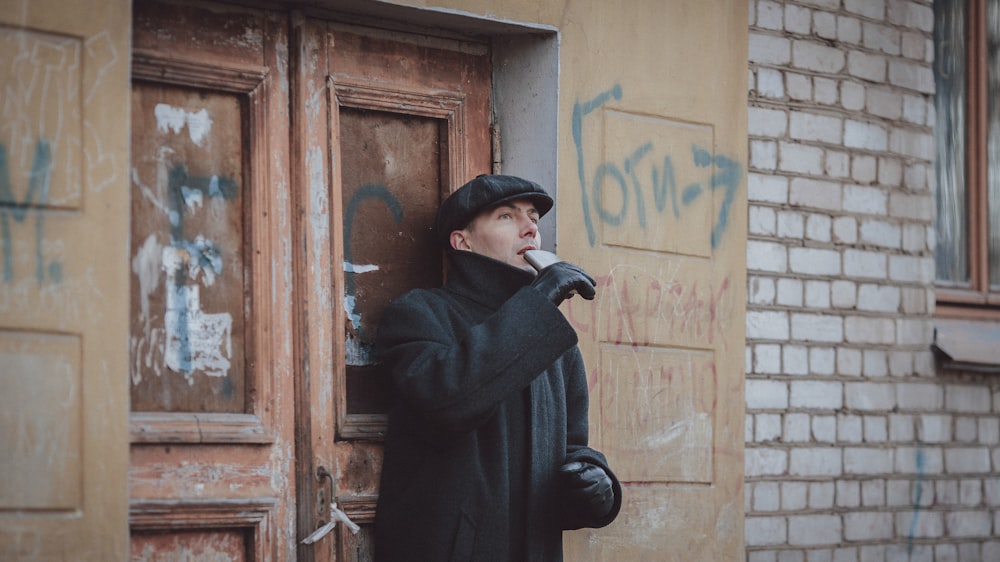 a person in a black coat and hat smoking a cigarette