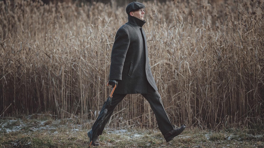 une personne en costume noir marchant dans les hautes herbes