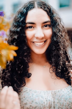 Close-up of soft, bouncy spiral curls framing a smiling young woman’s face.