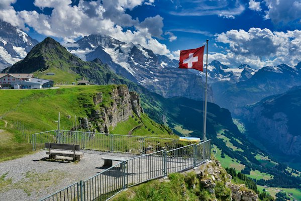 A flag on a pole in front of a mountain range — Grindelwald, Switzerland