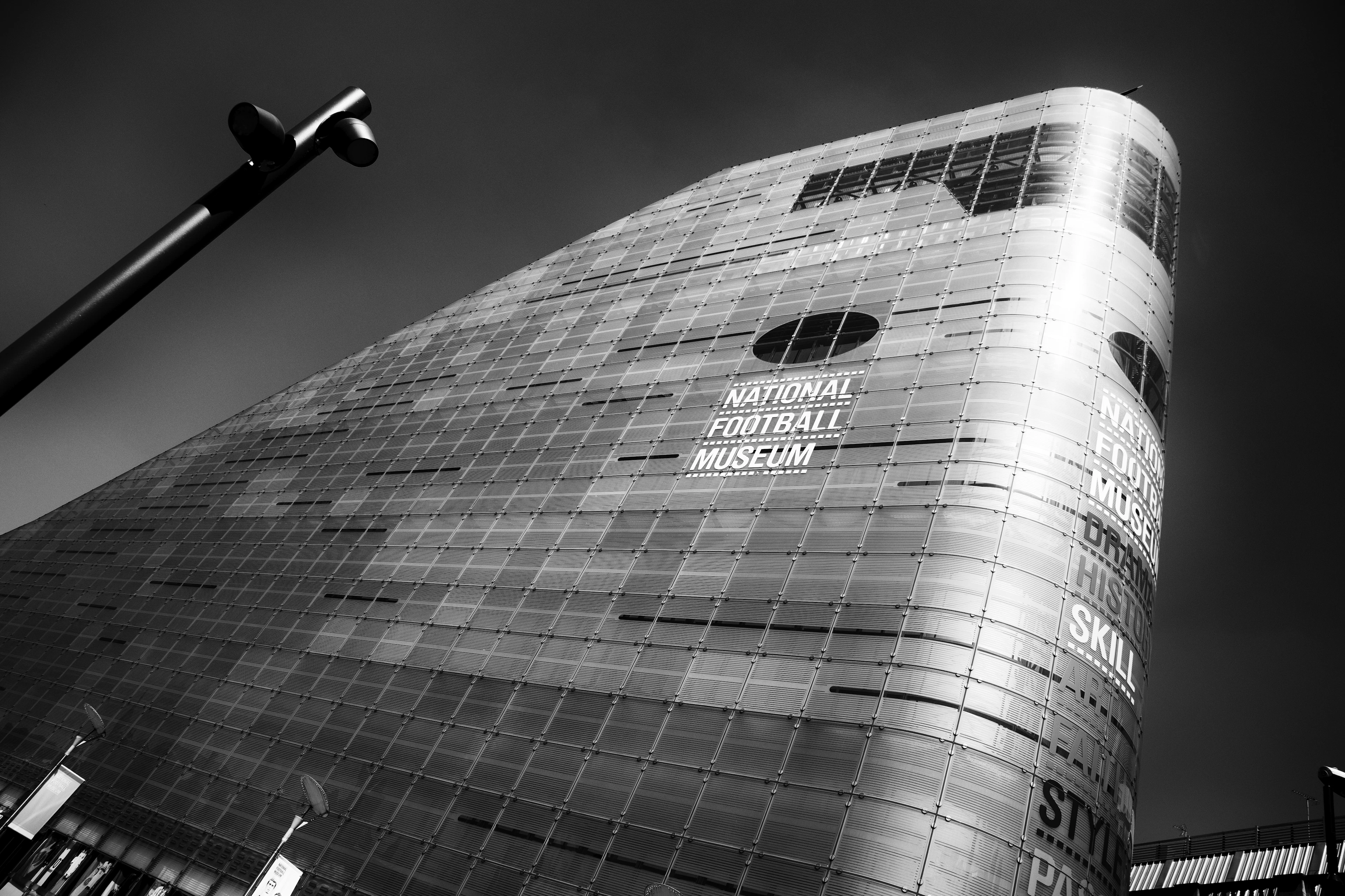 Low-angle black-and-white shot of the National Football Museum's curved glass facade