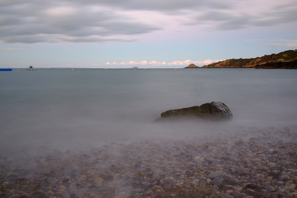 a rocky beach with a body of water in the background