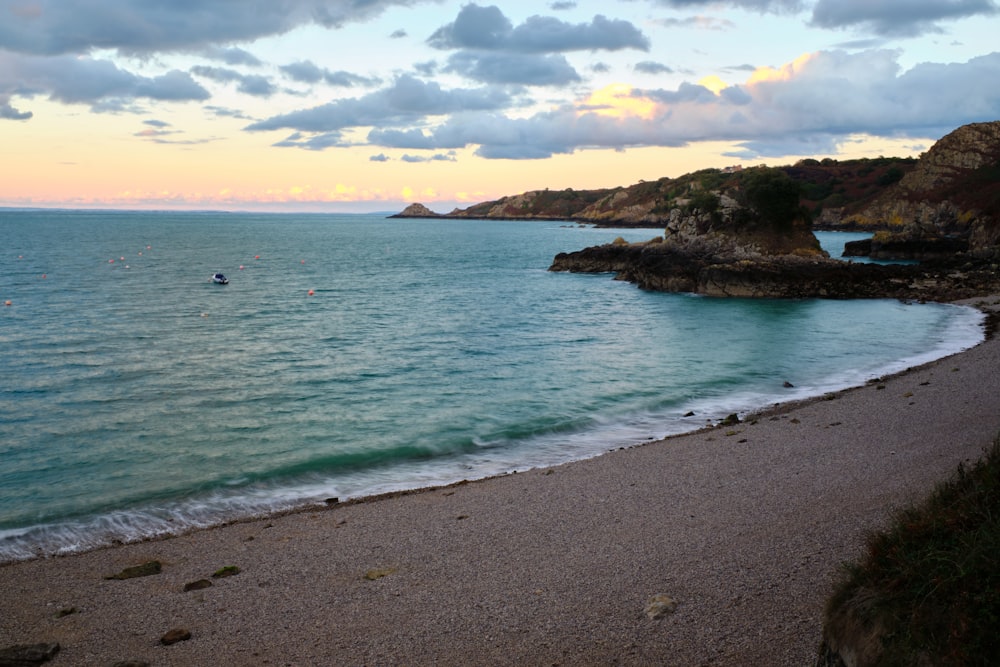 a beach with a body of water and a rocky shore