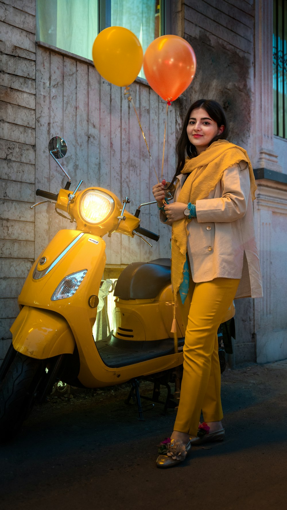 a person standing next to a yellow motorcycle with balloons