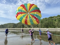 a group of people running in water with a parachute