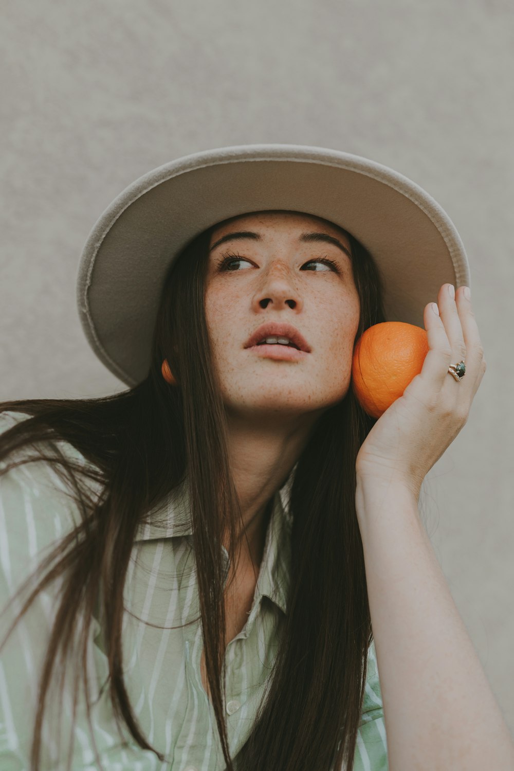 a woman wearing a hat and holding a carrot