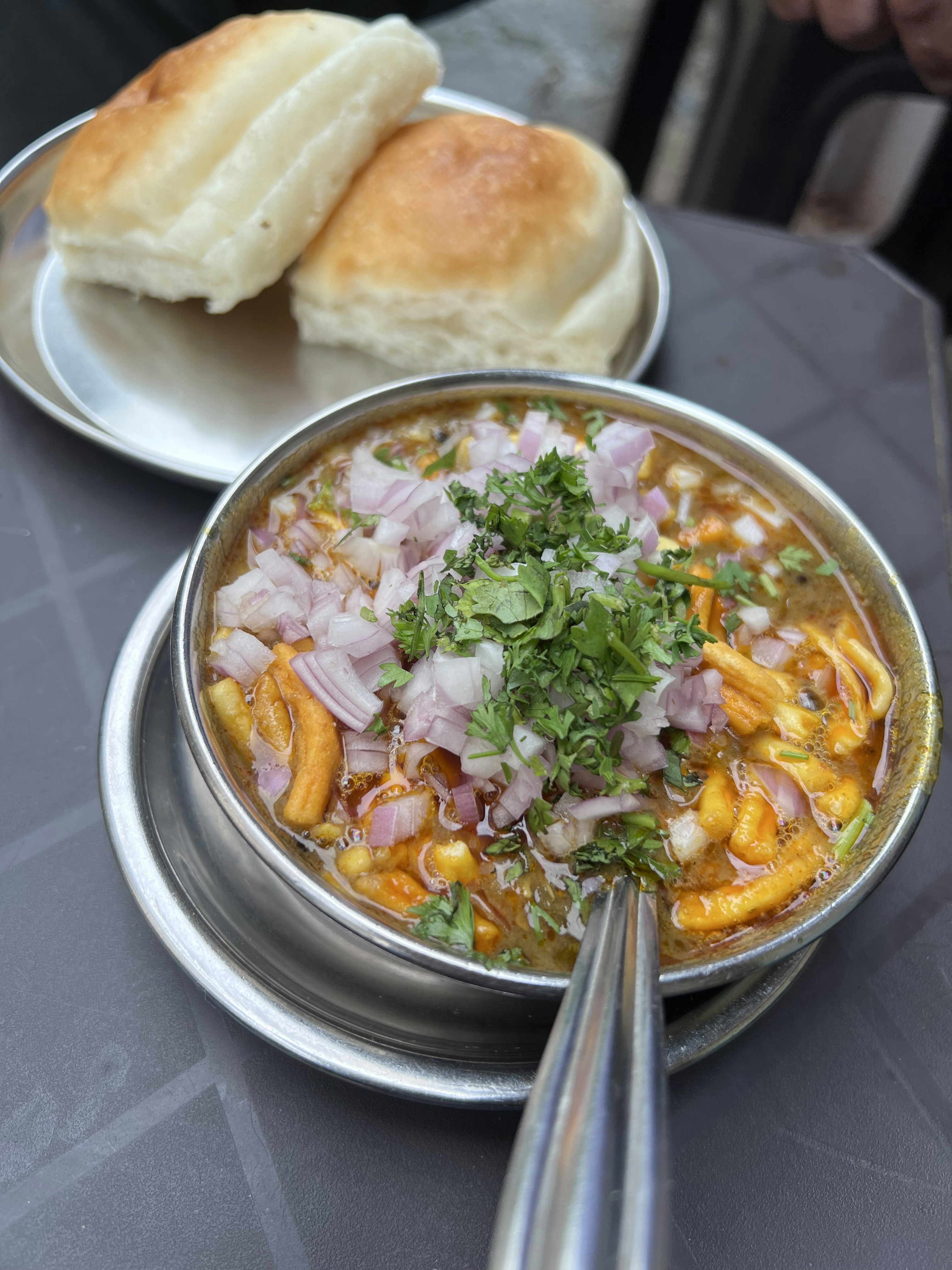 Pune misal pav in bowl with spicy moth bean curry, crispy sev, and buttered pav, vibrant orange and red food photography