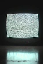 A digital TV screen glowing with yellow and white light on a black background.