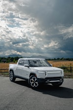 Red pickup truck parked on a rugged terrain under a dramatic sky.