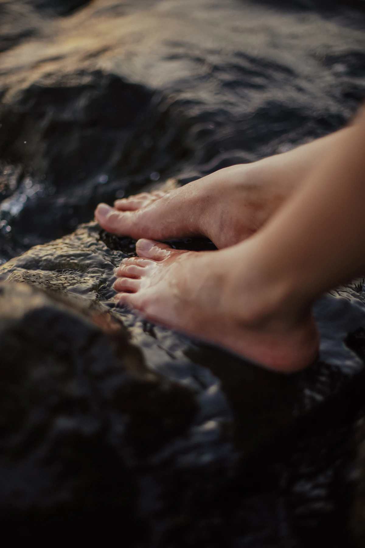 Bare feet resting on a smooth rock by a stream, a reminder of the quiet tissue your shoes are protecting
