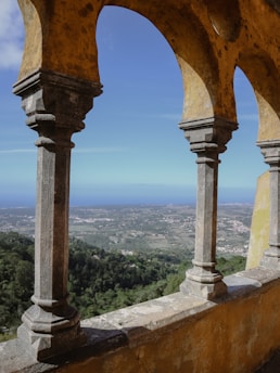 A breathtaking view of Pravčická brána arch framed by lush green forest under a clear blue sky.
