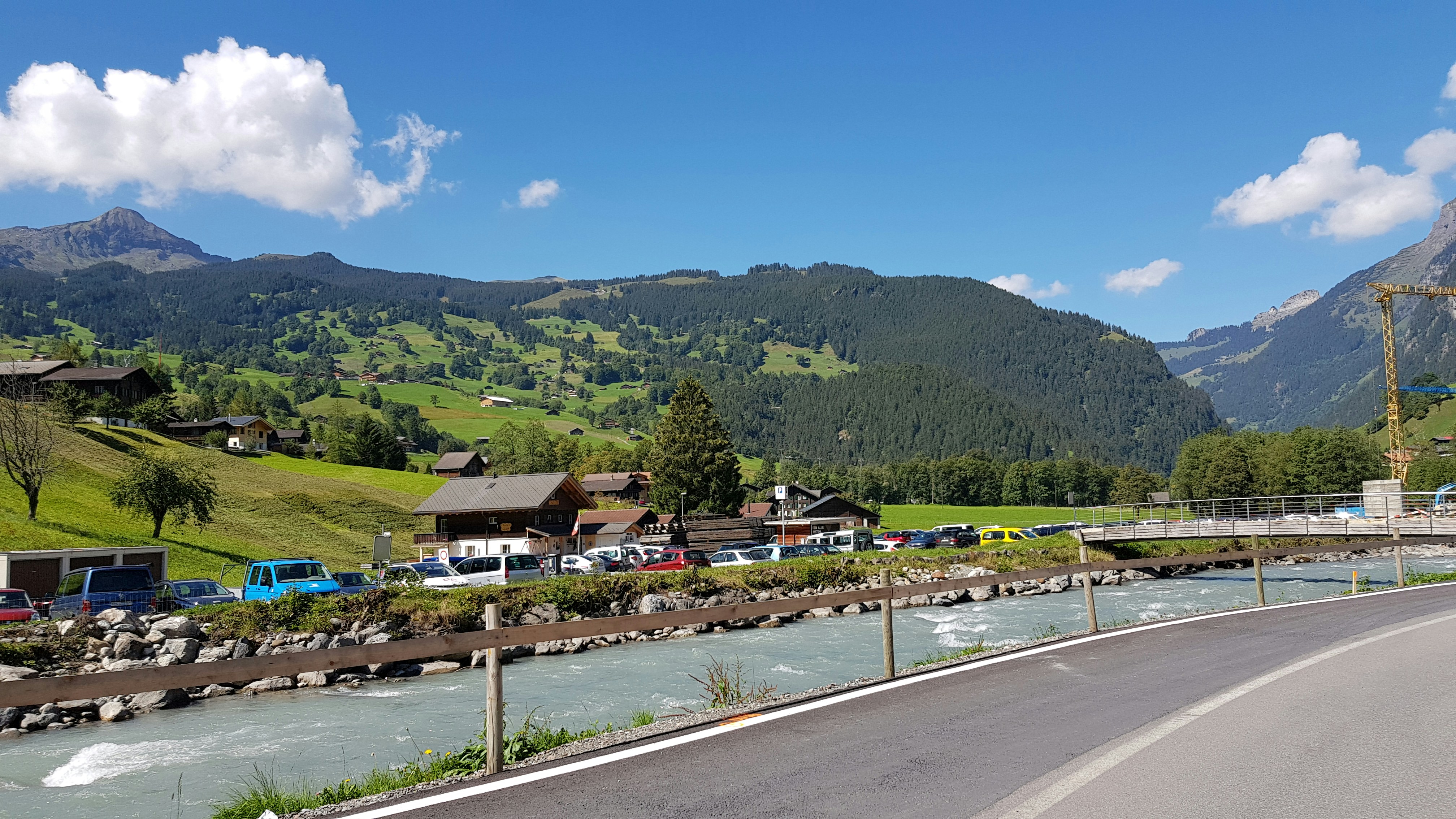 a road with cars and houses along it and mountains in the background